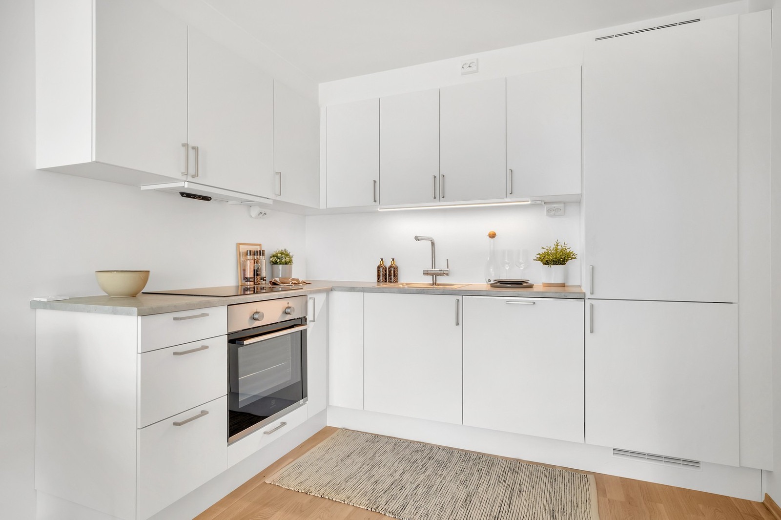 Moderne kjøkken med integrerte hvitevarer som komfyr, platetopp, oppvaskmaskin og kombiskap med kjøl/frys